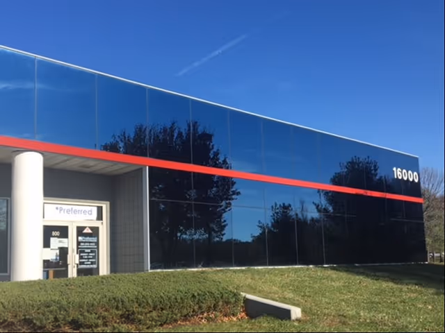 Modern glass-fronted building with a red stripe and a single entrance.