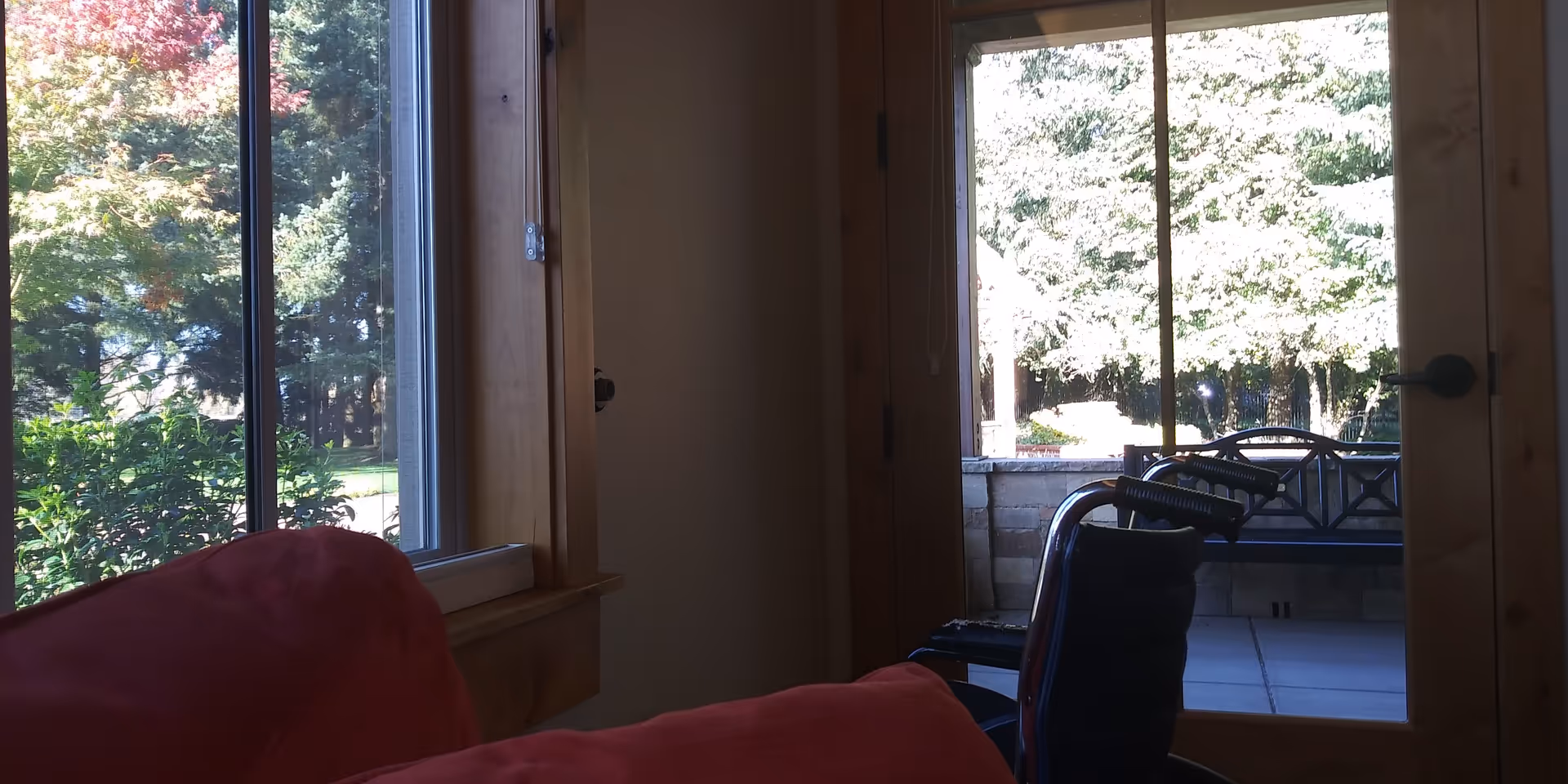 Interior room with a red couch and doorway opening to a sunny outdoor patio.