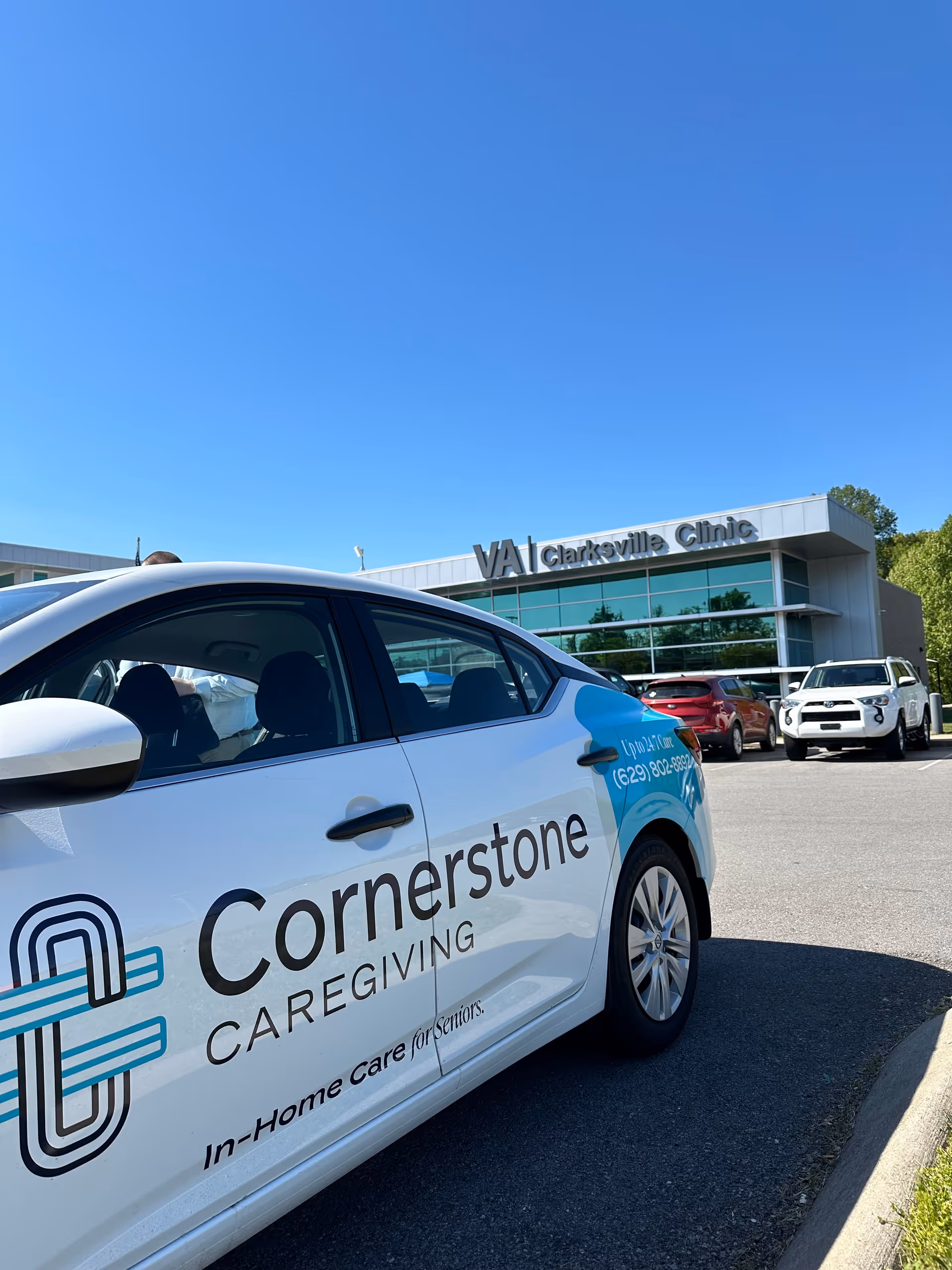 White Cornerstone Caregiving vehicle parked in front of a VA Clarksville Clinic building.