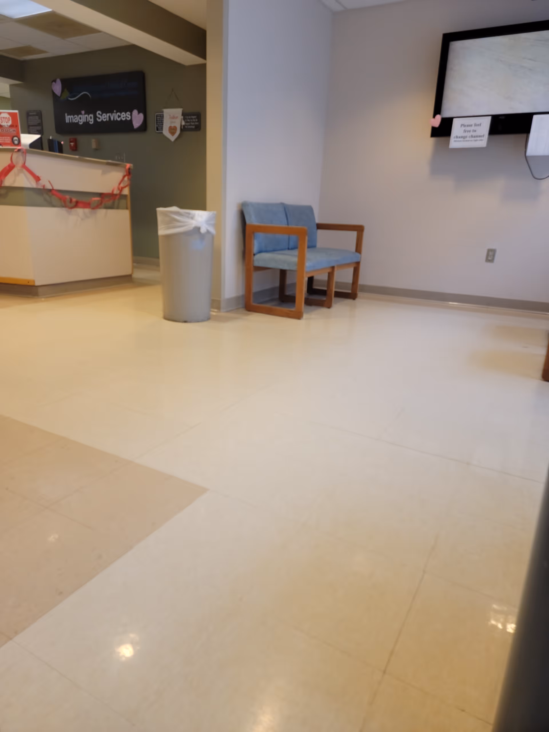 Lobby area with a reception desk, trash can, and blue chairs in a medical center.
