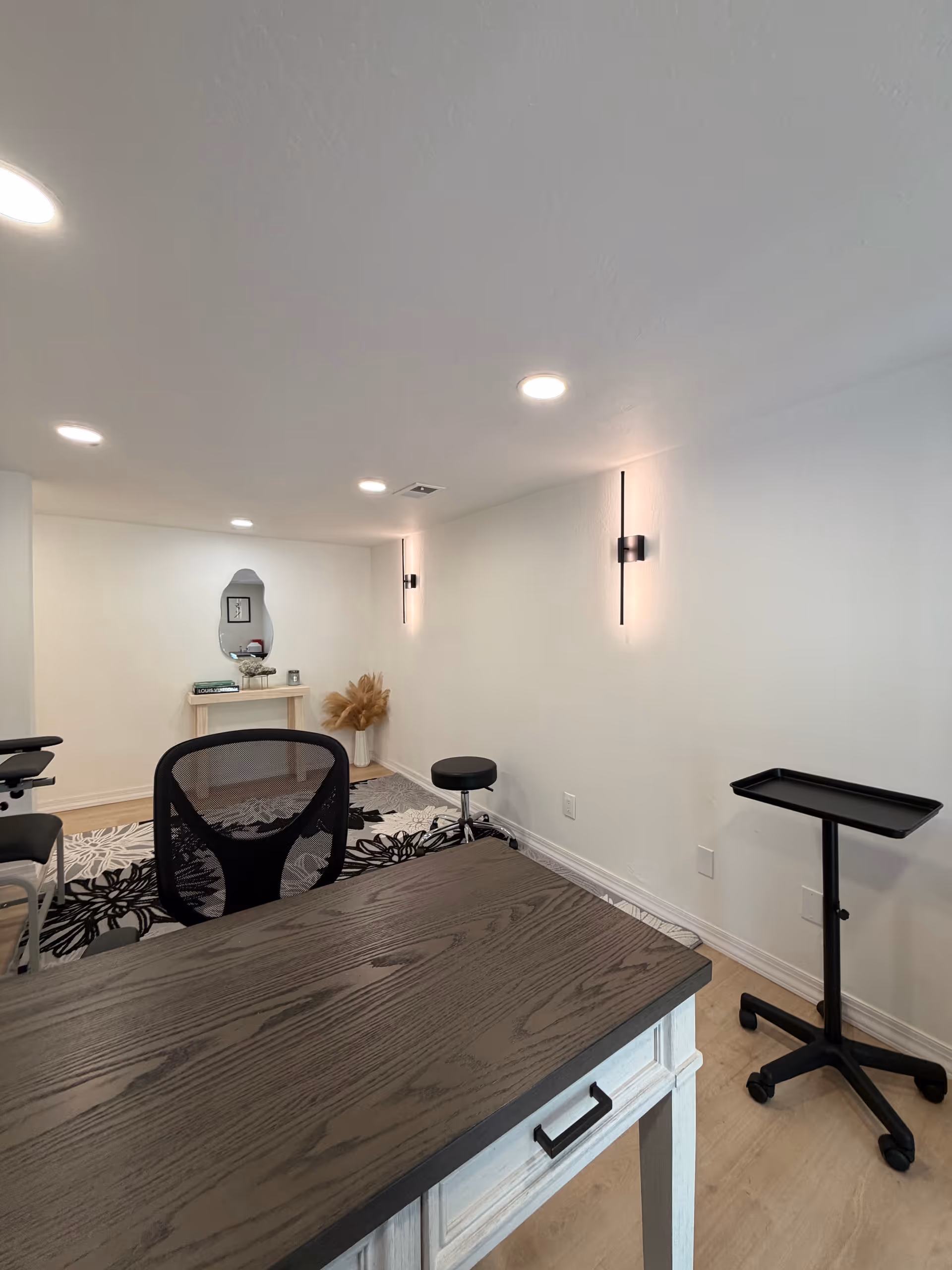 Bright, minimalist interior with desk, chair, rolling stool, and back wall vanity.