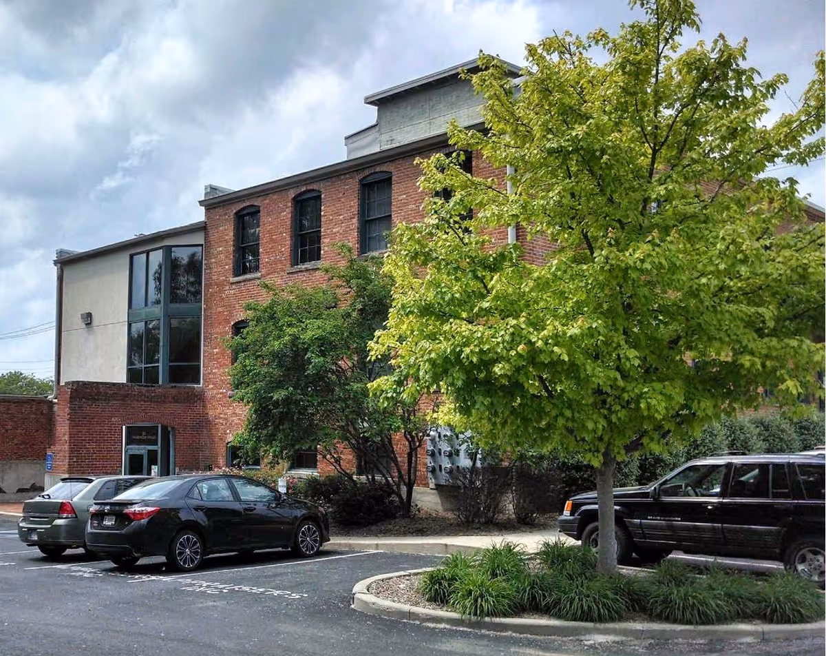 Exterior view of Adaptive Nursing and Healthcare Services building with cars and trees.