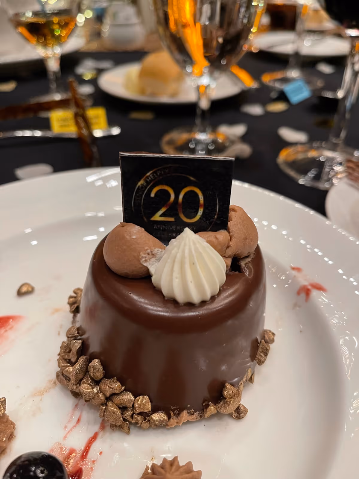 Chocolate dessert with glossy glaze on plate, topped with cream shapes and chocolate truffles.