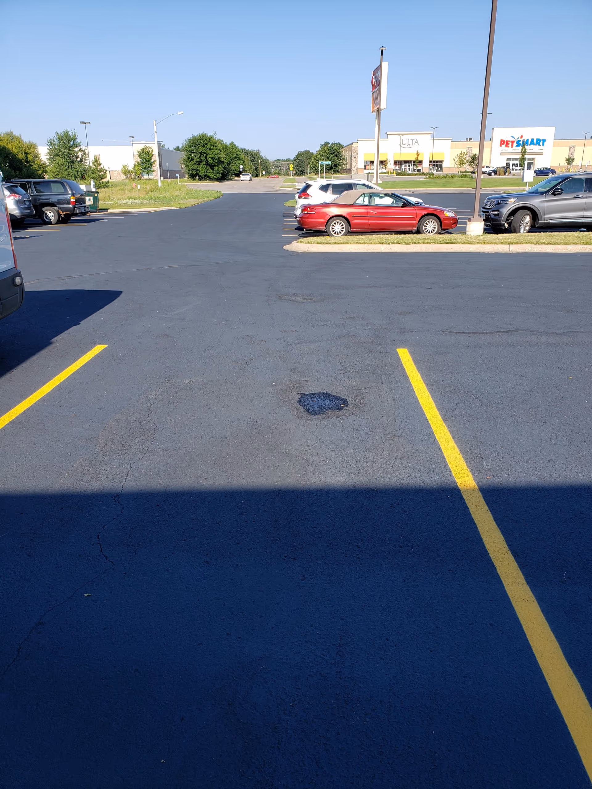 A spacious parking lot in front of a shopping plaza with parked cars.