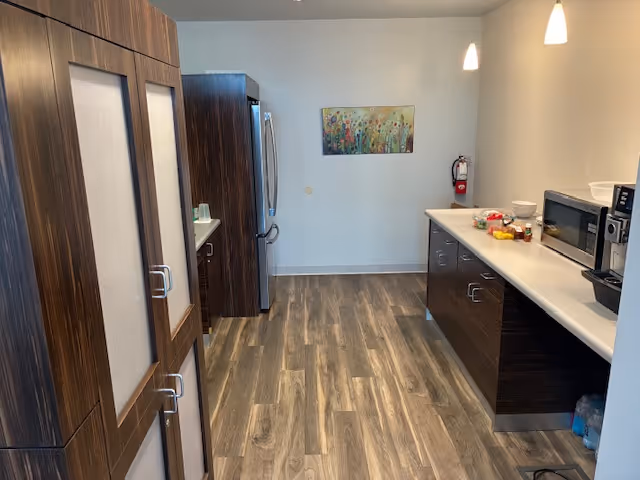 Modern kitchen in a senior living facility with dark wood cabinets and stainless appliances.
