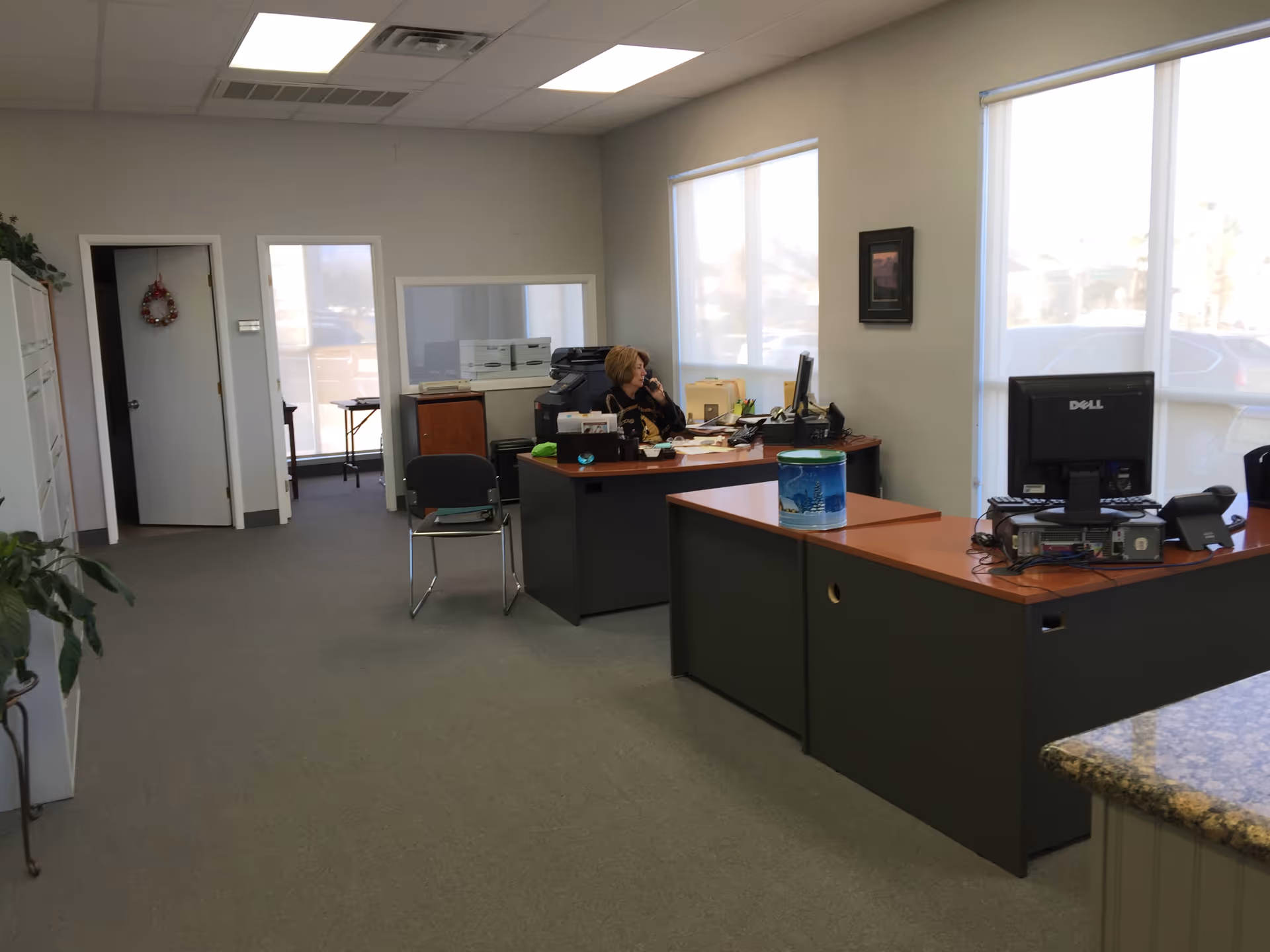 Office reception area with a receptionist at a desk and computer equipment.