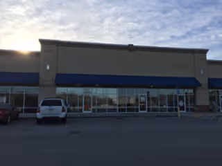 Exterior view of Enhabit Home Health building with glass doors and blue awnings.
