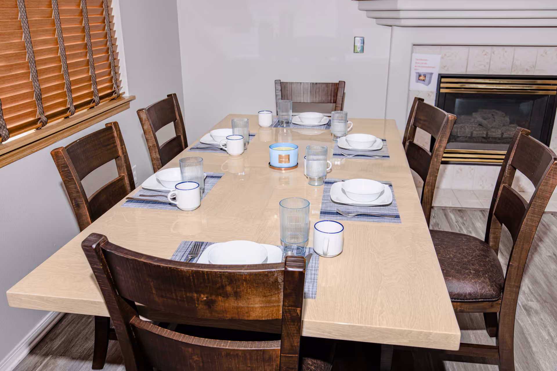 Long wooden dining table set with bowls, mugs, and glasses in a cozy dining room.
