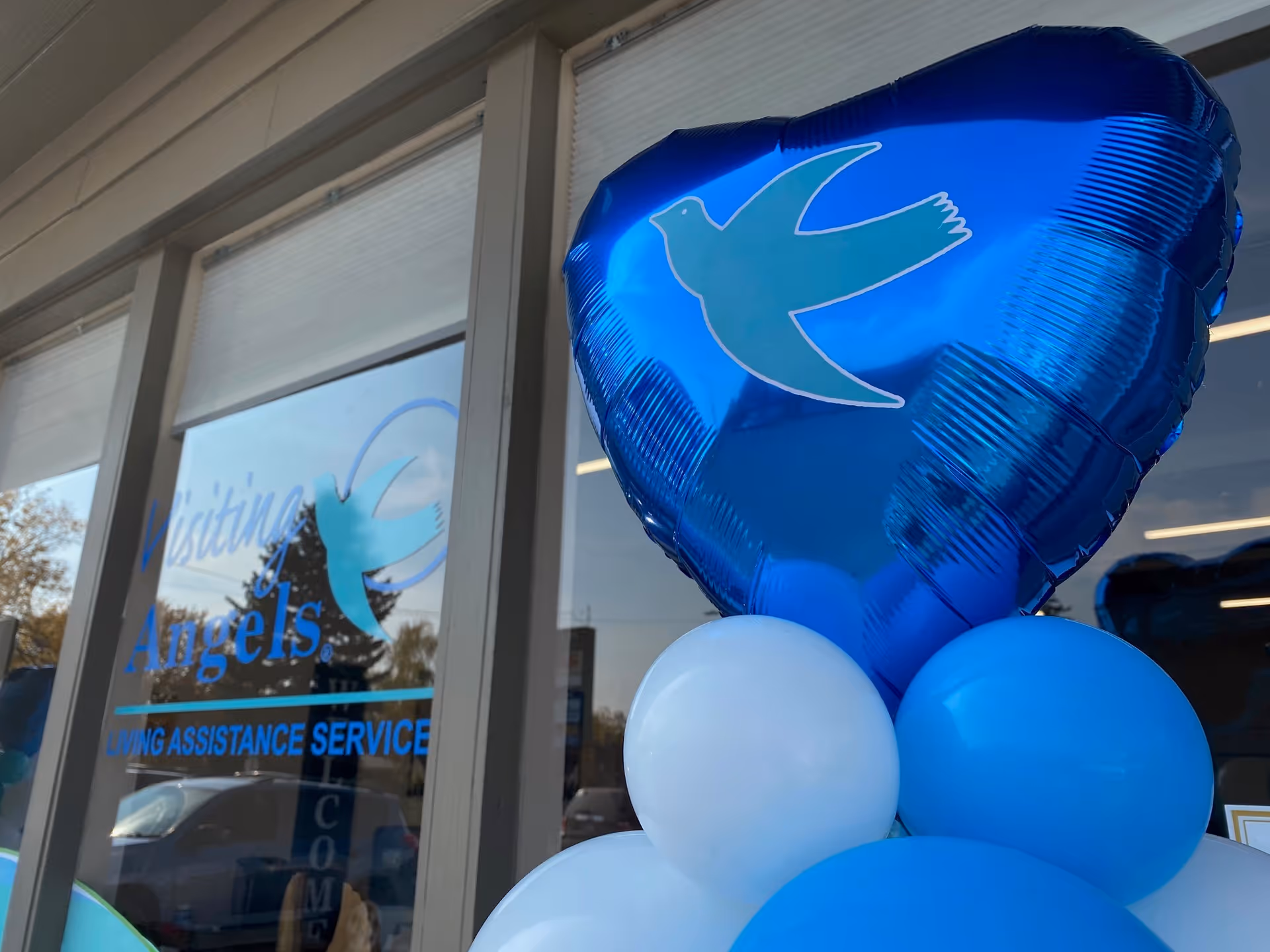 Exterior storefront of Visiting Angels Senior Home Care with blue balloons.