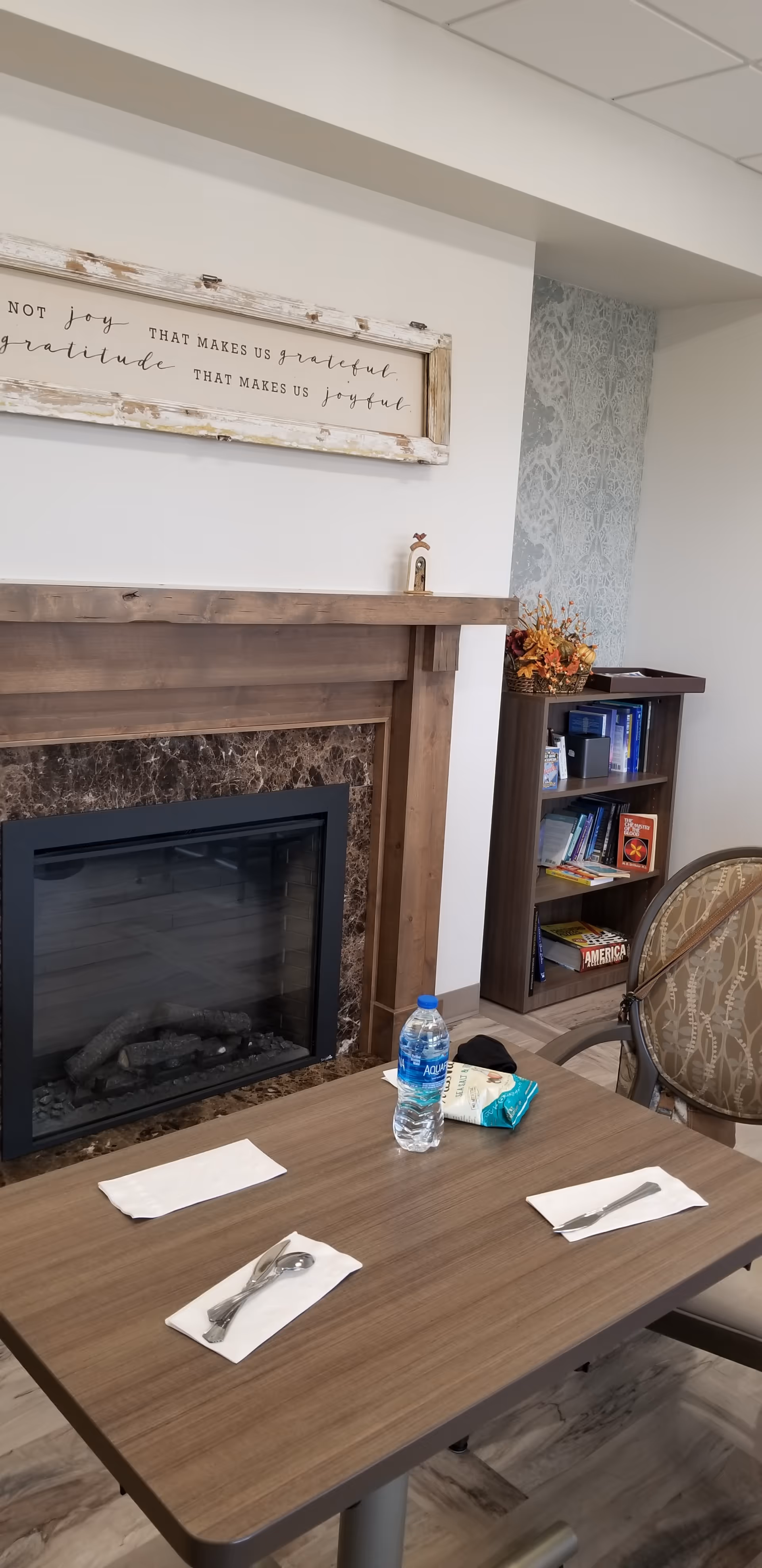 Cozy dining area with a fireplace, table set for two, and a bookshelf nearby.