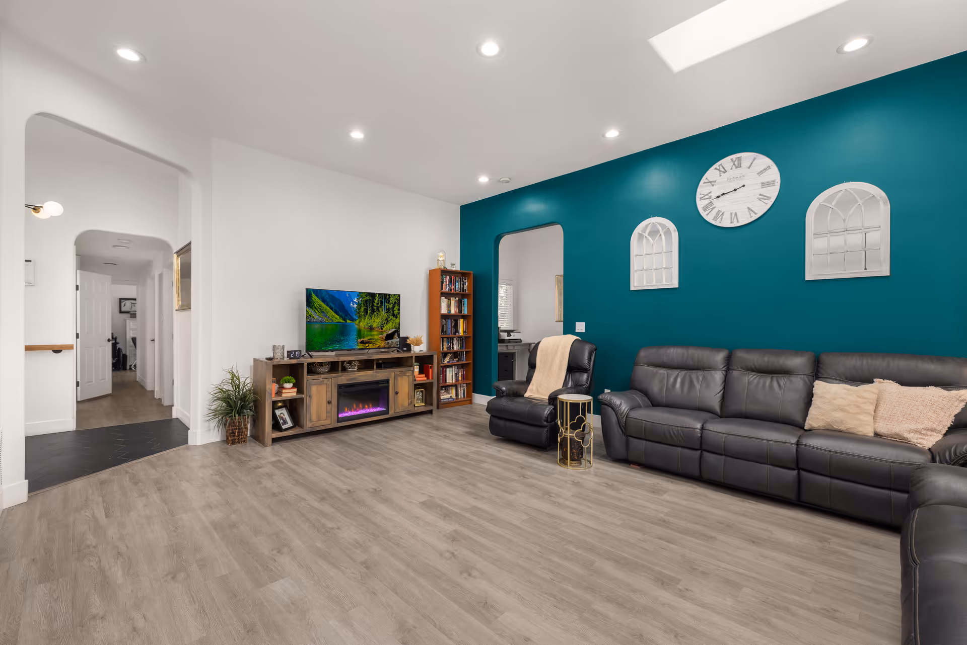 Spacious modern living area with teal accent wall, large sectional sofa, TV, and fireplace.