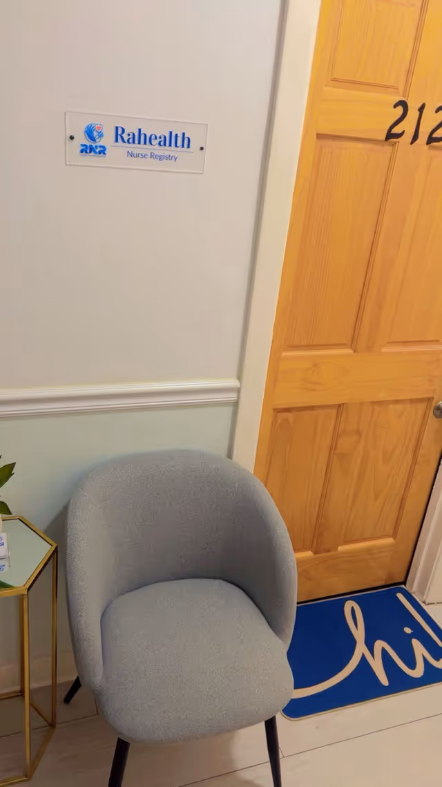Interior lobby corner with a Rahealth Nurse Registry sign and a gray upholstered chair.