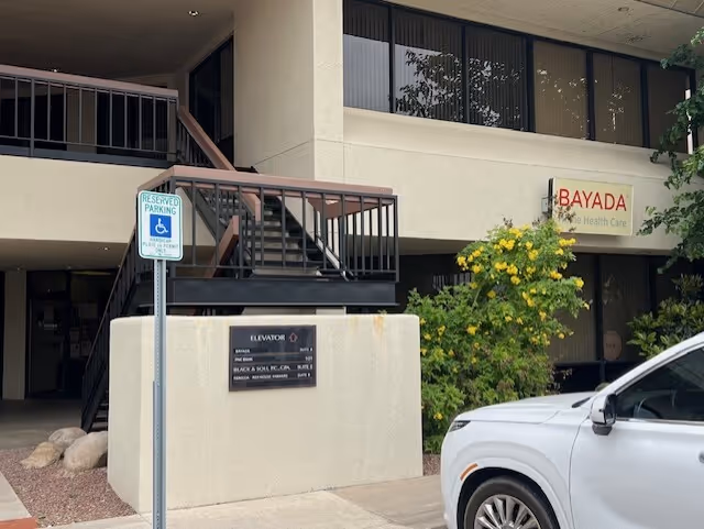 Exterior view of BAYADA Assistive Care facility with entrance, stairs, ramp, and a parked car.