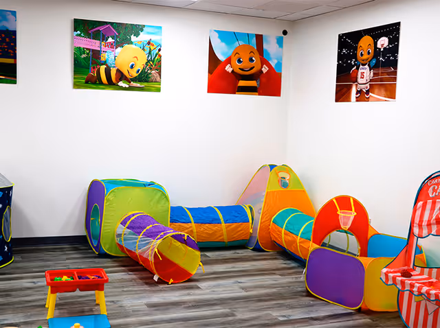 Colorful children's play area with tunnels and soft toys inside a clean interior room.