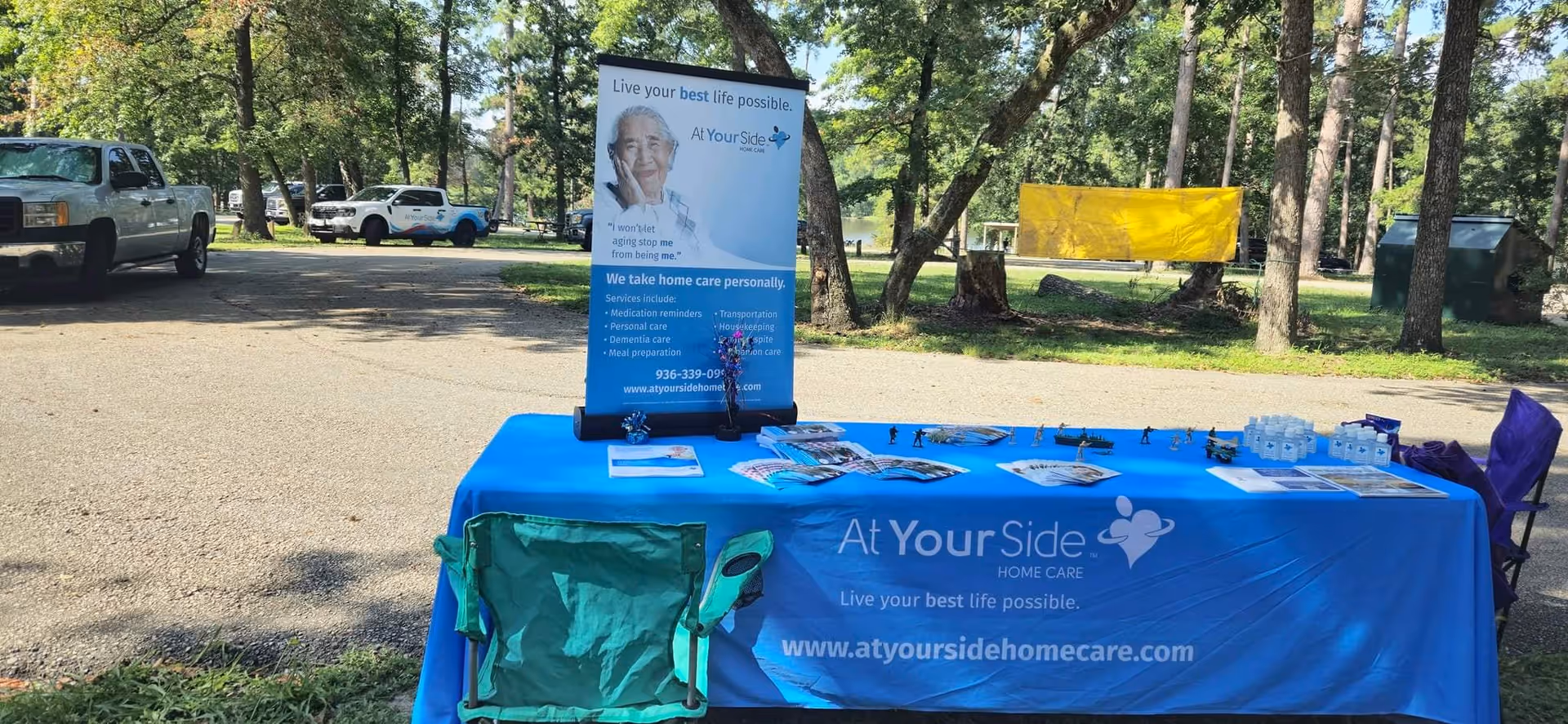 Outdoor info table with blue cloth and banner advertising At Your Side Home Care.