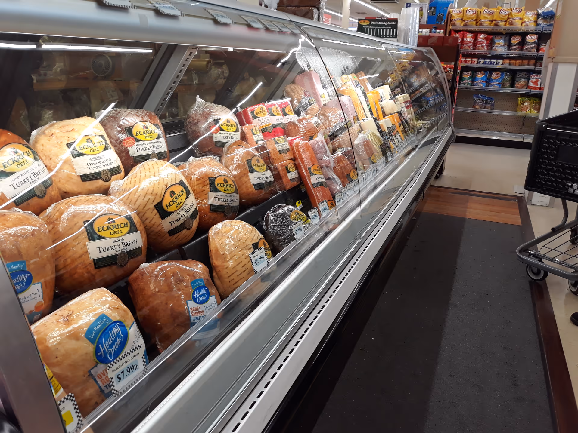 Refrigerated deli case filled with assorted meats inside a grocery store.