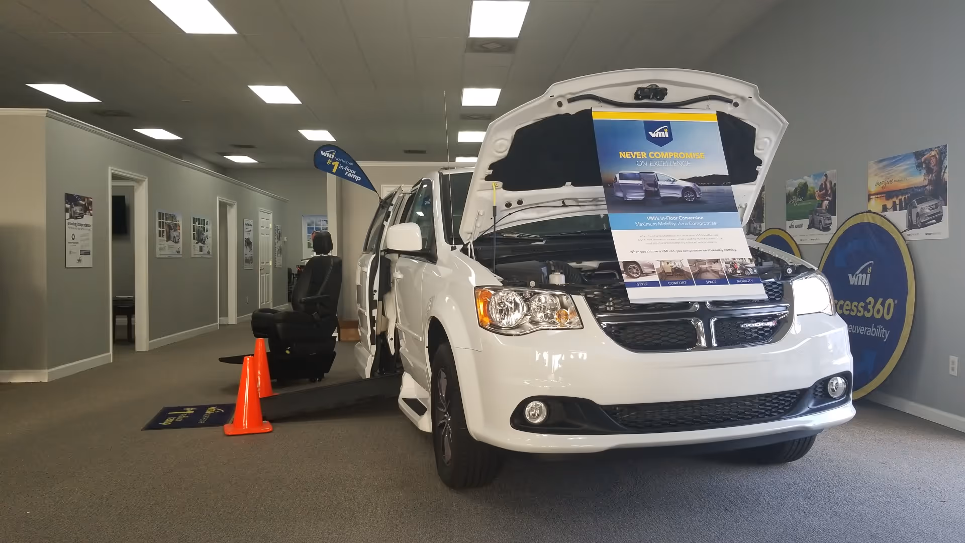 White mobility van on display inside a MobilityWorks showroom with ramp, posters, and a person.