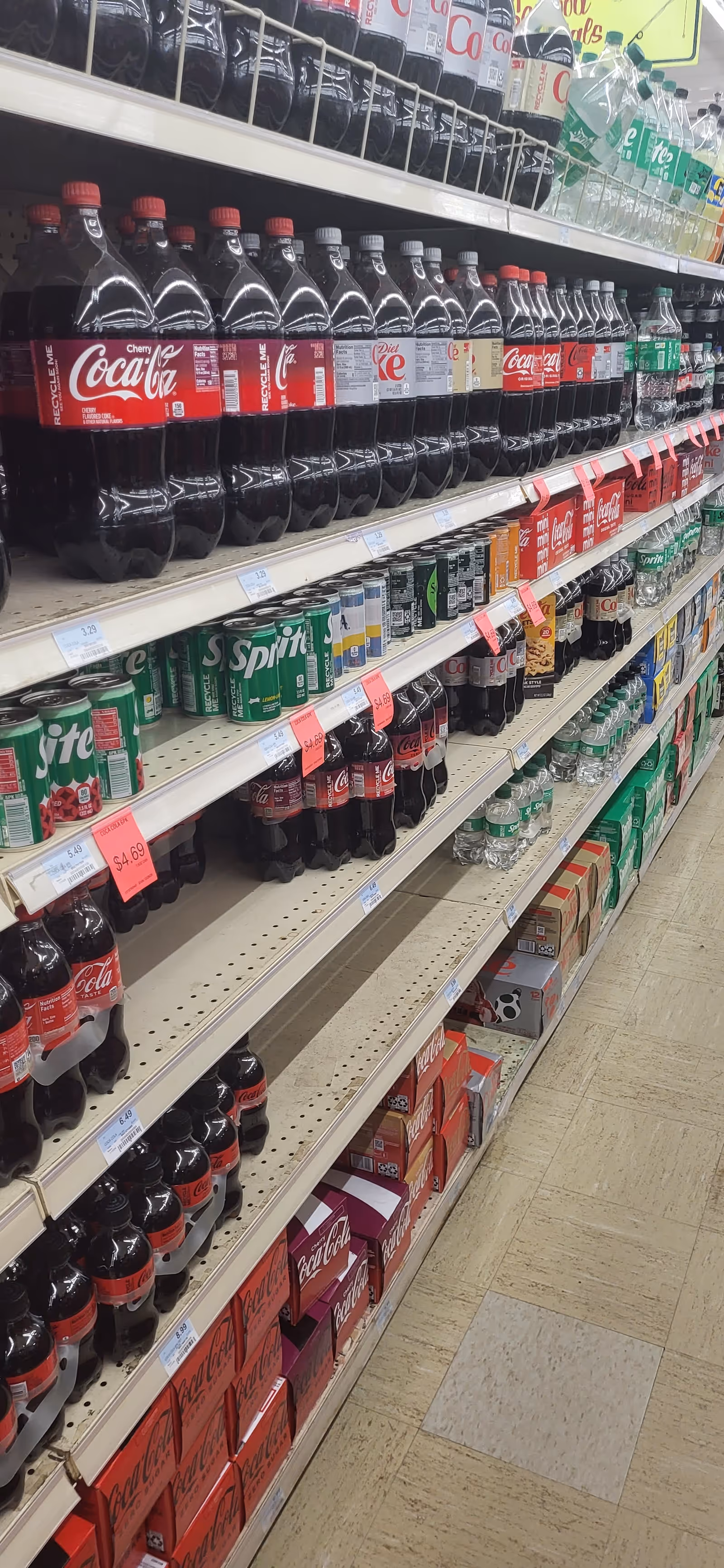 Store aisle filled with soda bottles, including Coca-Cola, on shelves.