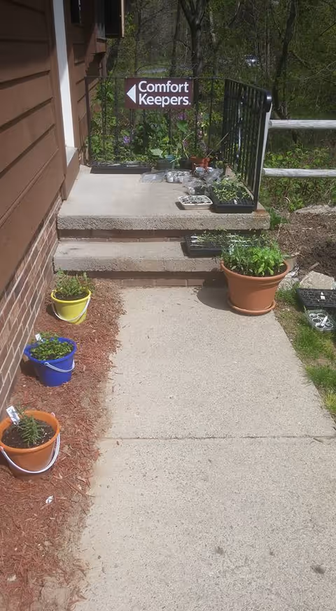 Front entrance of Comfort Keepers Home Care with potted plants along a concrete walkway