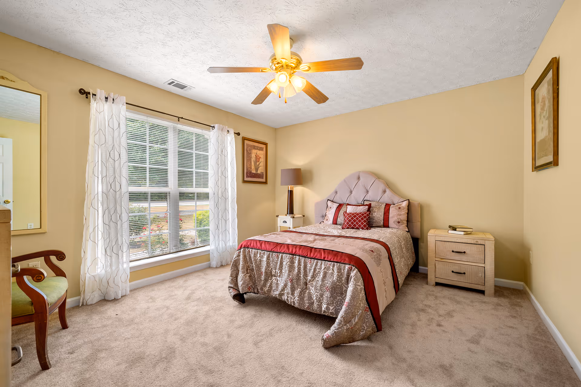 Bedroom with a bed, nightstands, window, and soft beige walls in a senior care home.