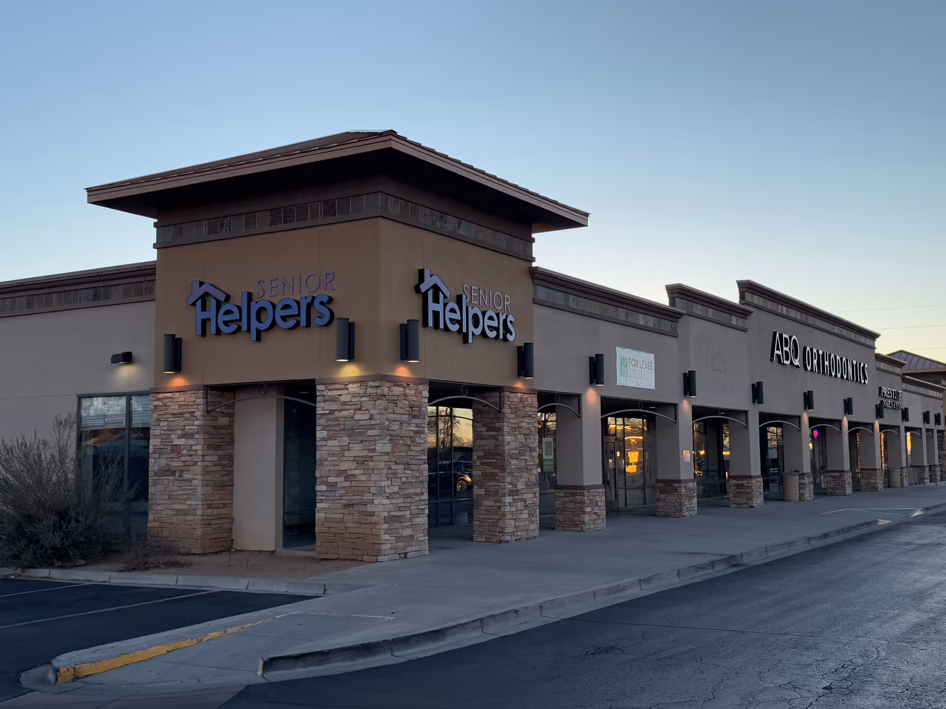 Exterior view of a strip mall storefront with Senior Helpers signage and stone columns.