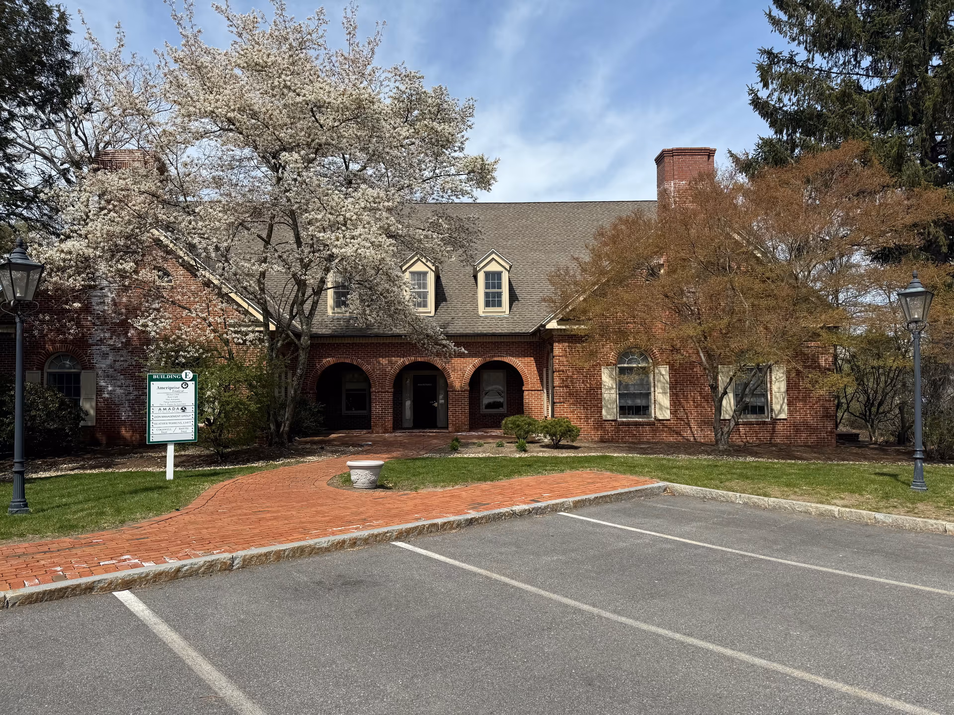 Brick senior living facility with arched entrance and blooming trees in front.