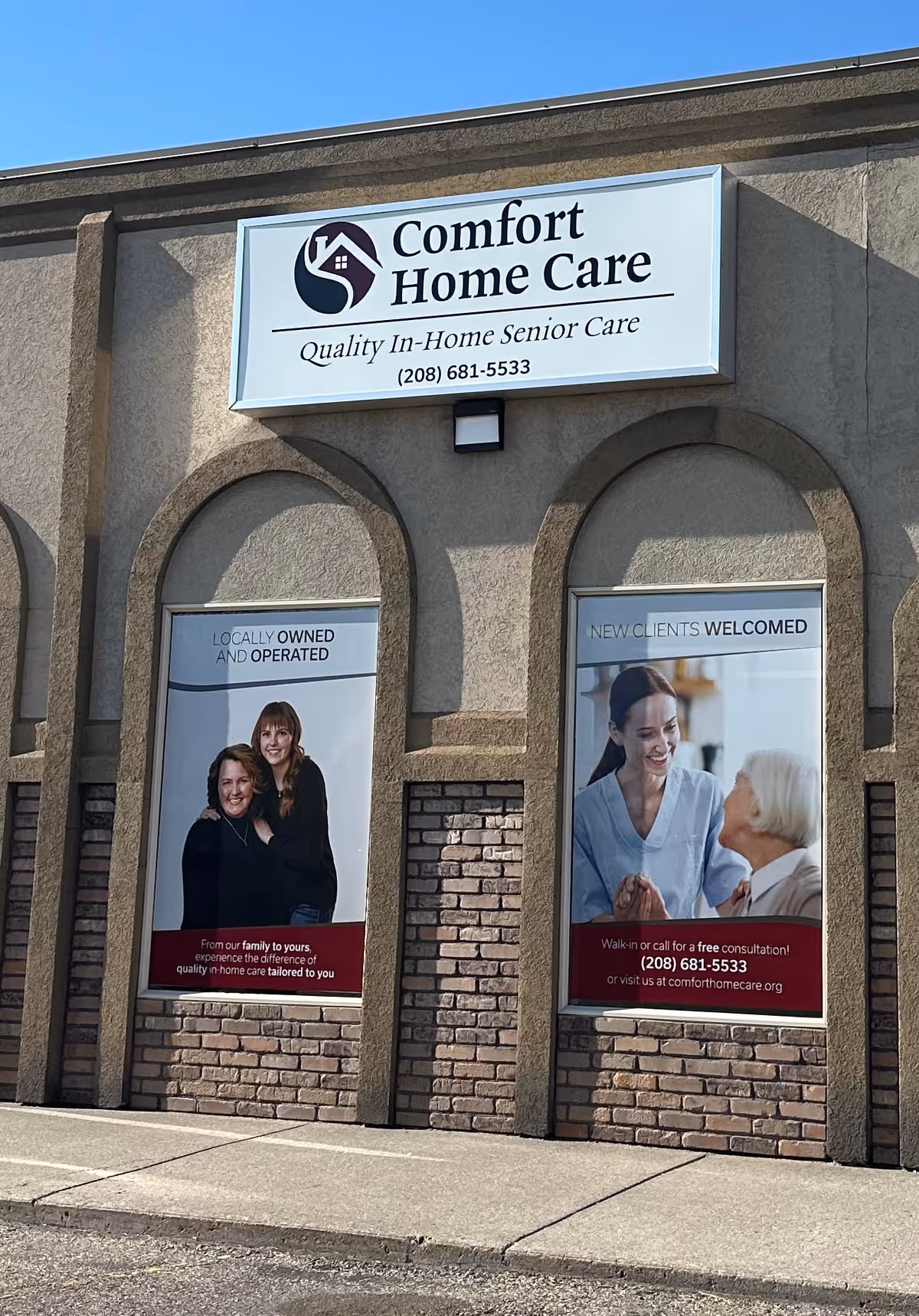 Exterior of a Comfort Home Care building with a large sign and two posters in windows.