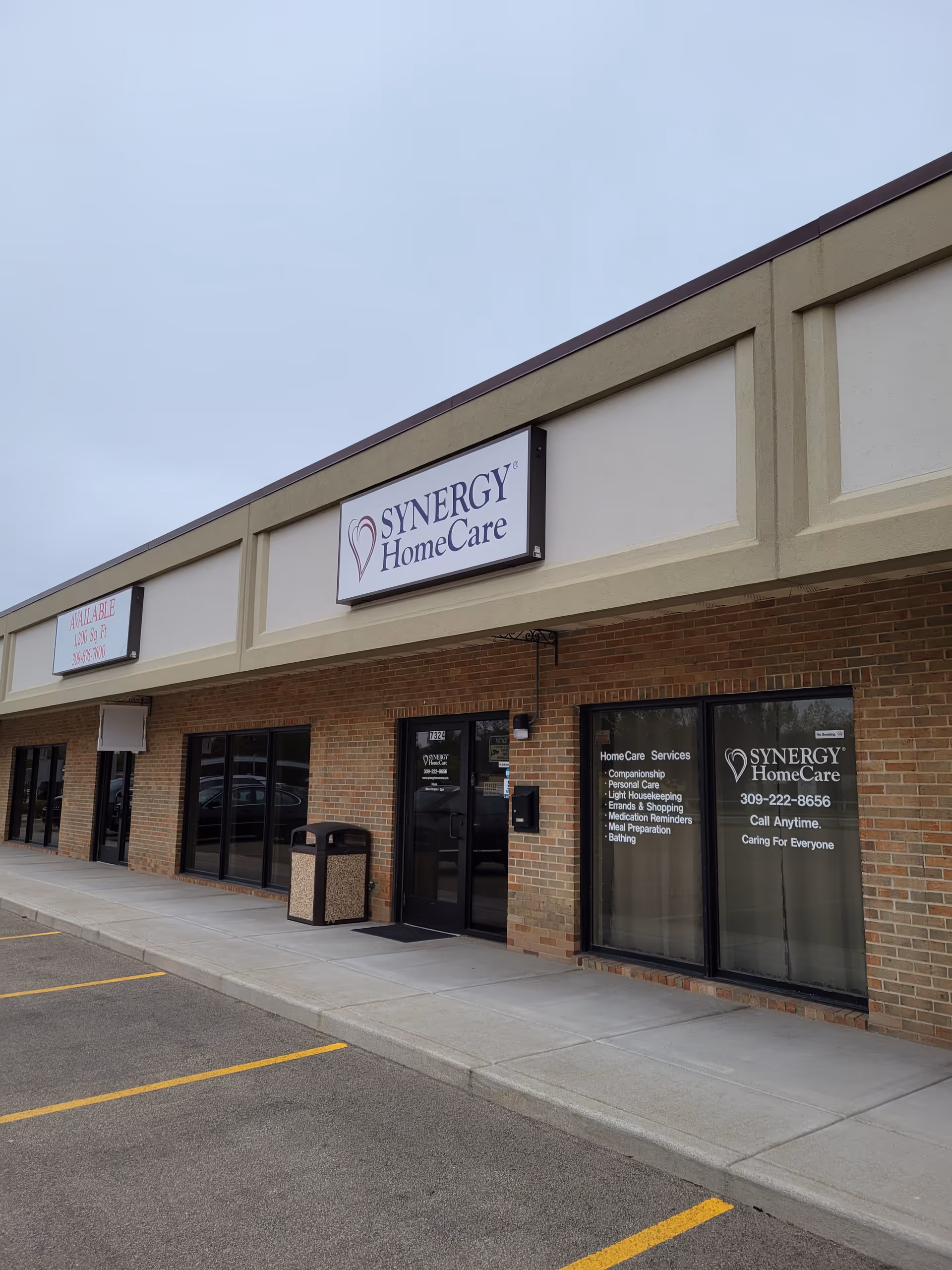 Exterior view of a Synergy HomeCare storefront with brick facade and glass doors.