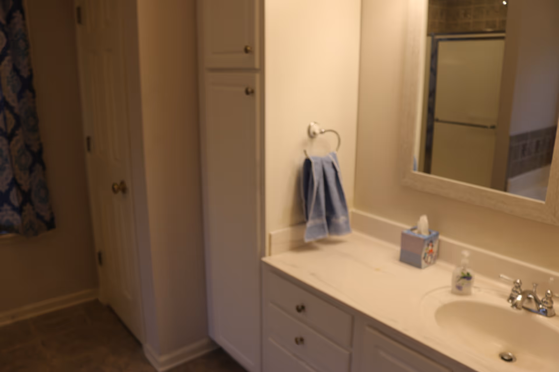 Bathroom vanity with sink, marble countertop, mirror, towel ring, and a shower area.