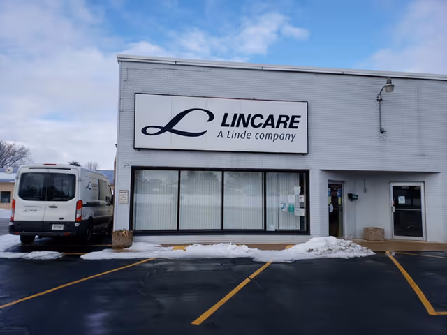 Front view of LINCARE building with sign, windows, van, and snowy parking lot.