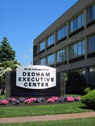 Exterior view of a modern office building with a sign and colorful flowers