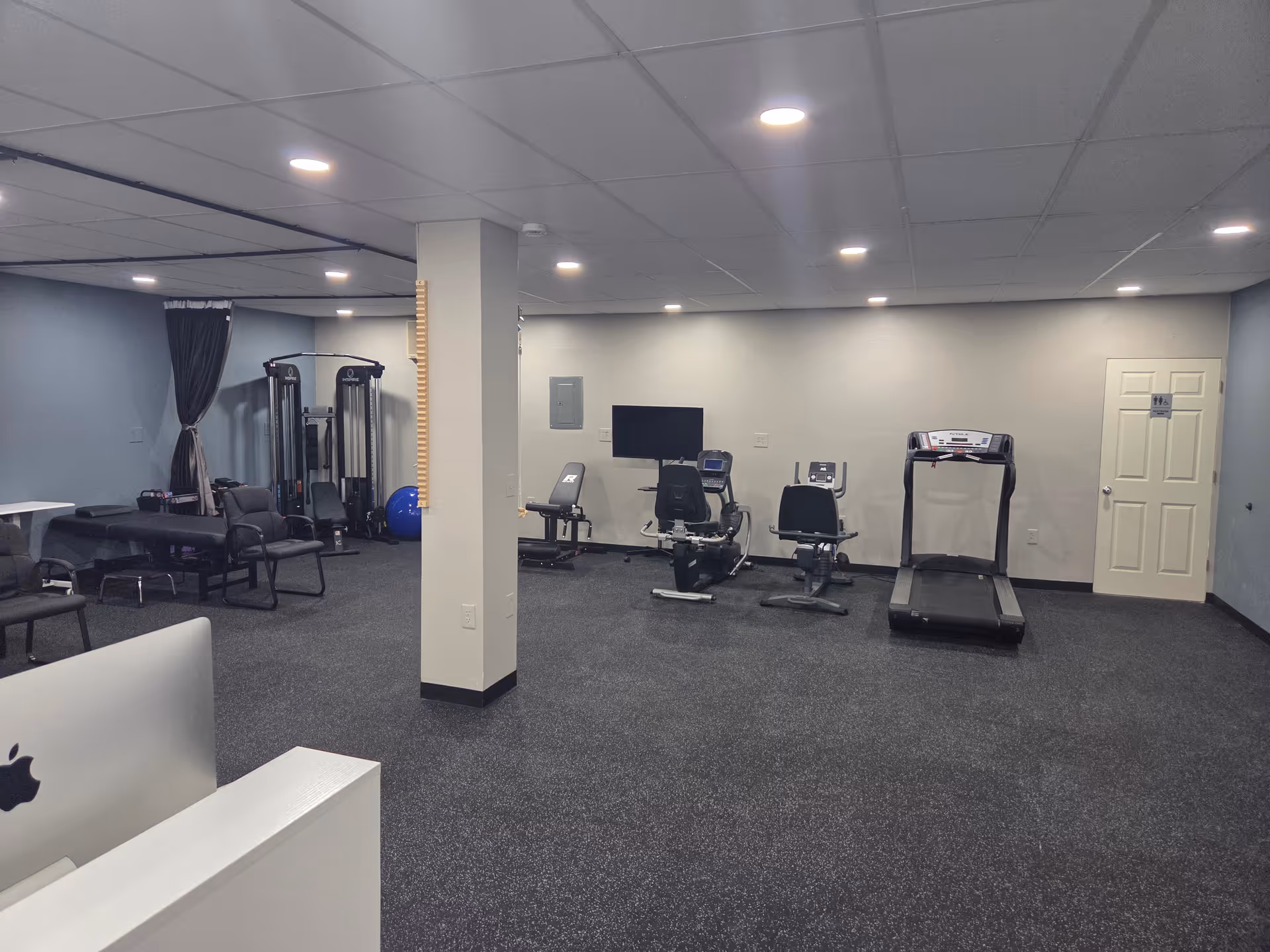 A spacious senior wellness gym with treadmills, bikes, and weight machines.
