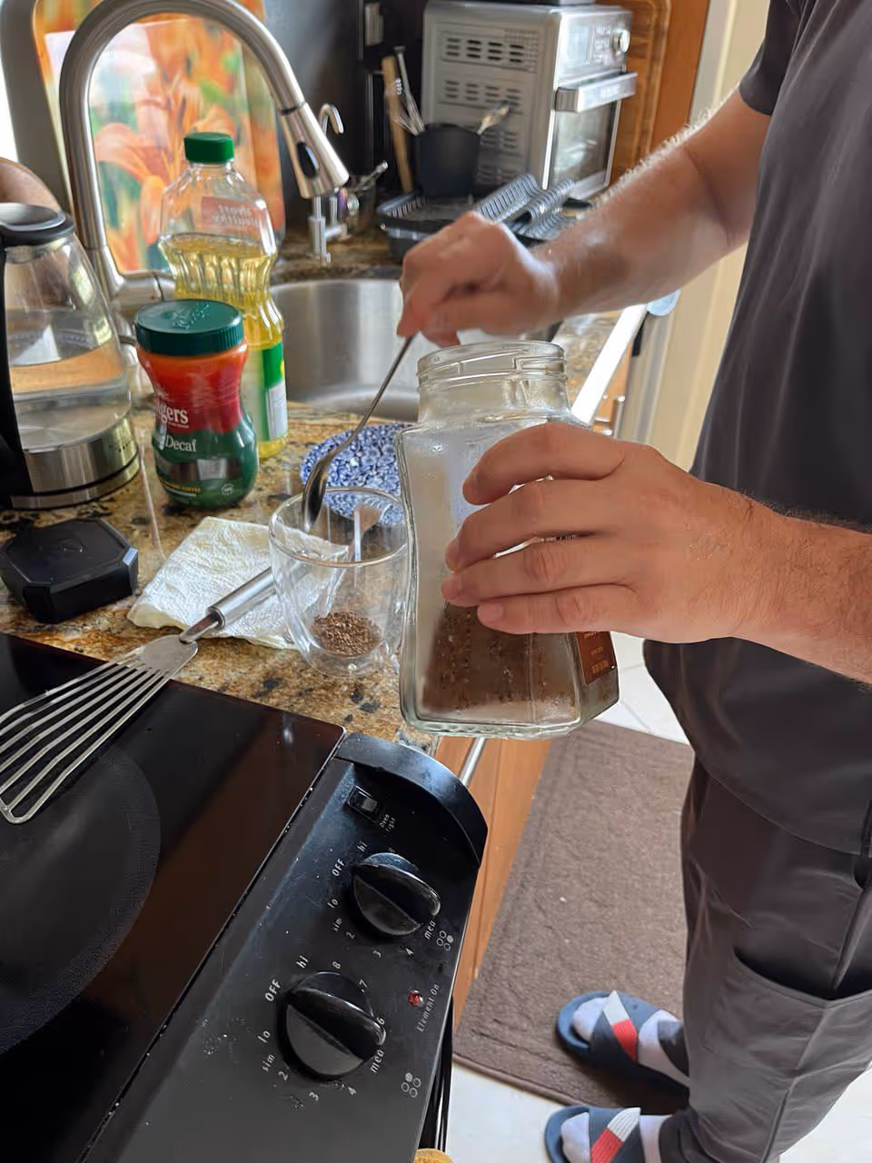 Person pours water into a mason jar at a kitchen counter.