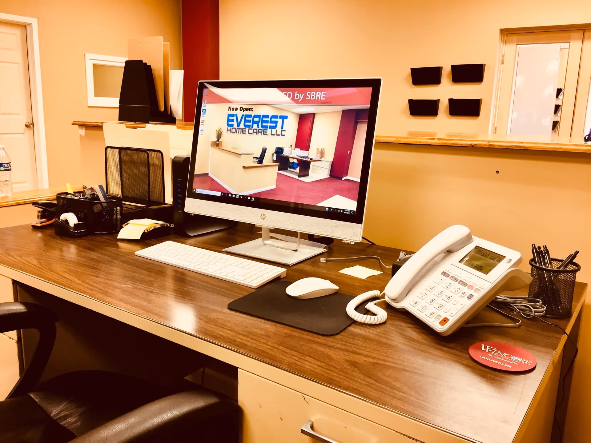 Reception desk with computer, phone, and office supplies inside Everest Home Care LLC lobby.