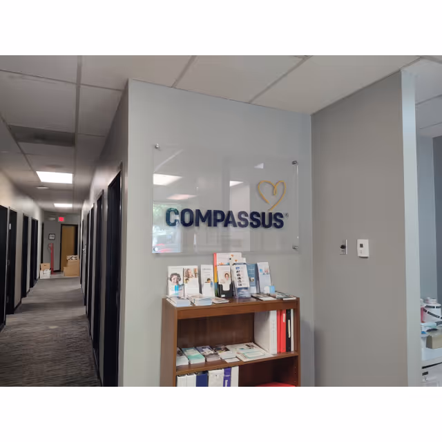 Interior office hallway featuring a Compassus sign, brochures on a wooden shelf.