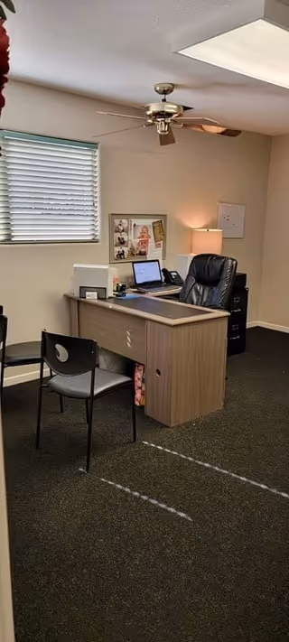 Office desk with laptop and chair in a small reception area at a senior living facility.