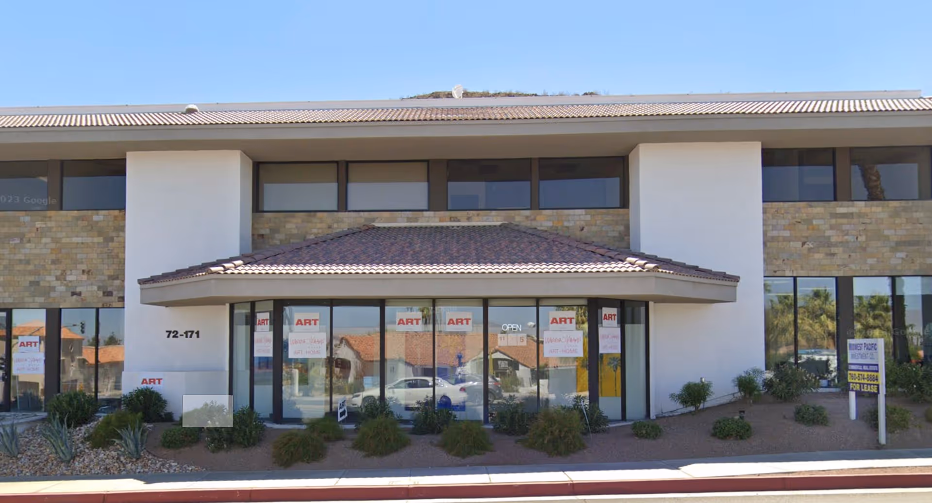 Two-story commercial building with glass storefronts and a tiled, covered entrance.