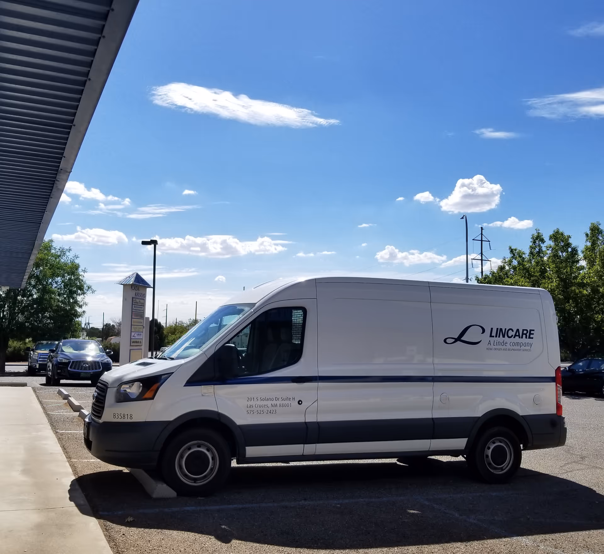 White Lincare van parked outside a facility against a blue sky.