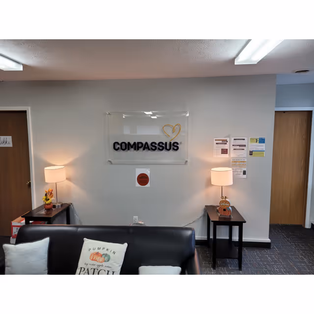 Lobby area featuring a Compassus sign, sofa, two lamps, and side tables.