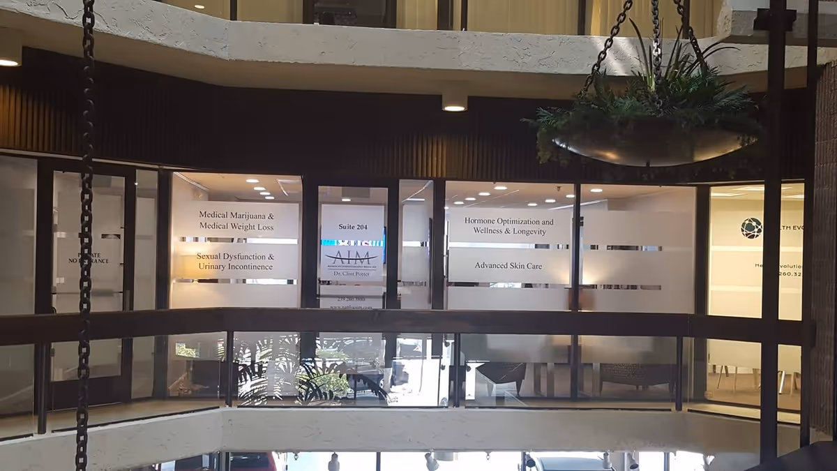 Lobby area of a medical building with frosted glass signs, glass doors, and a hanging planter.