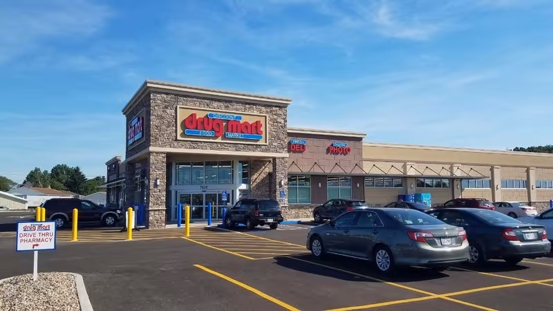 Front view of Discount Drug Mart exterior with parking lot and cars.