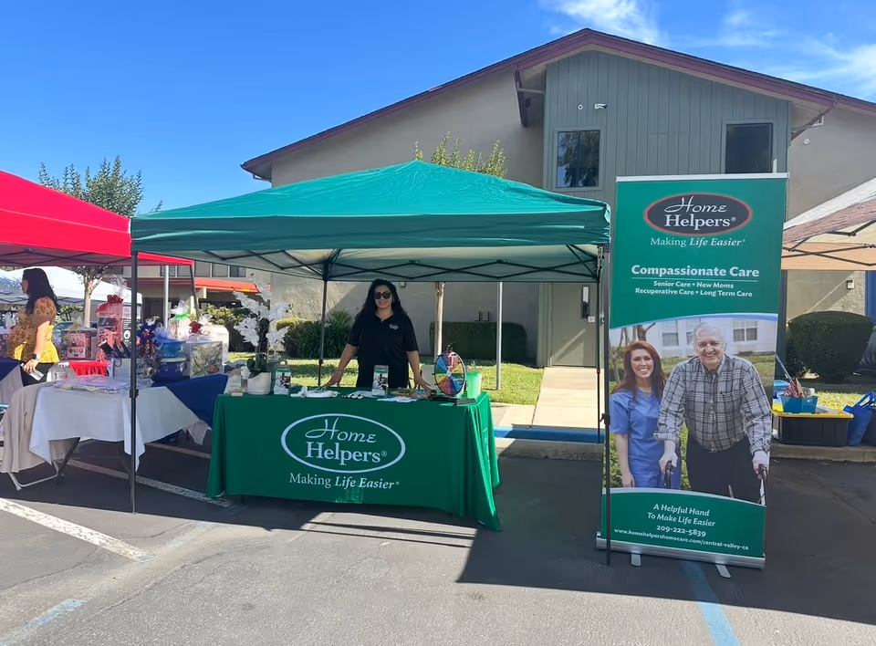 Outdoor Home Helpers booth with a green table, banner, and tents.