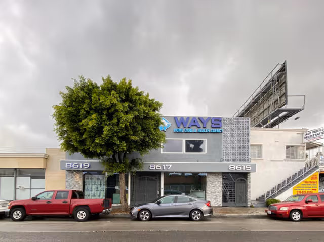 Exterior view of WAYS Home Care & Health Agency building along a street with parked cars.