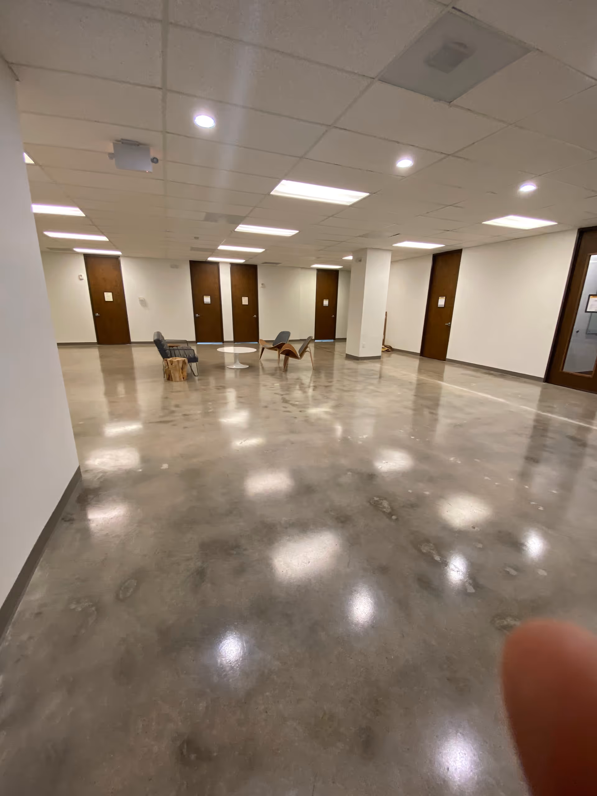 Empty interior corridor with polished concrete floor and a small seating area by doors.