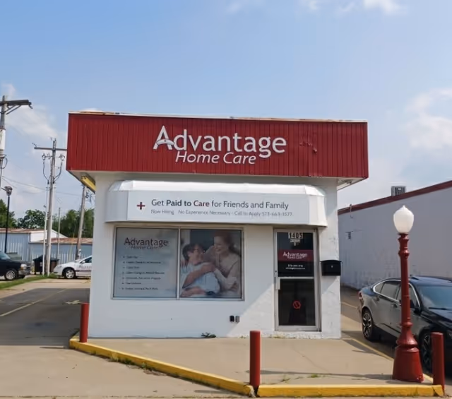 Front view of Advantage Home Care facility with red signage and white entry building.