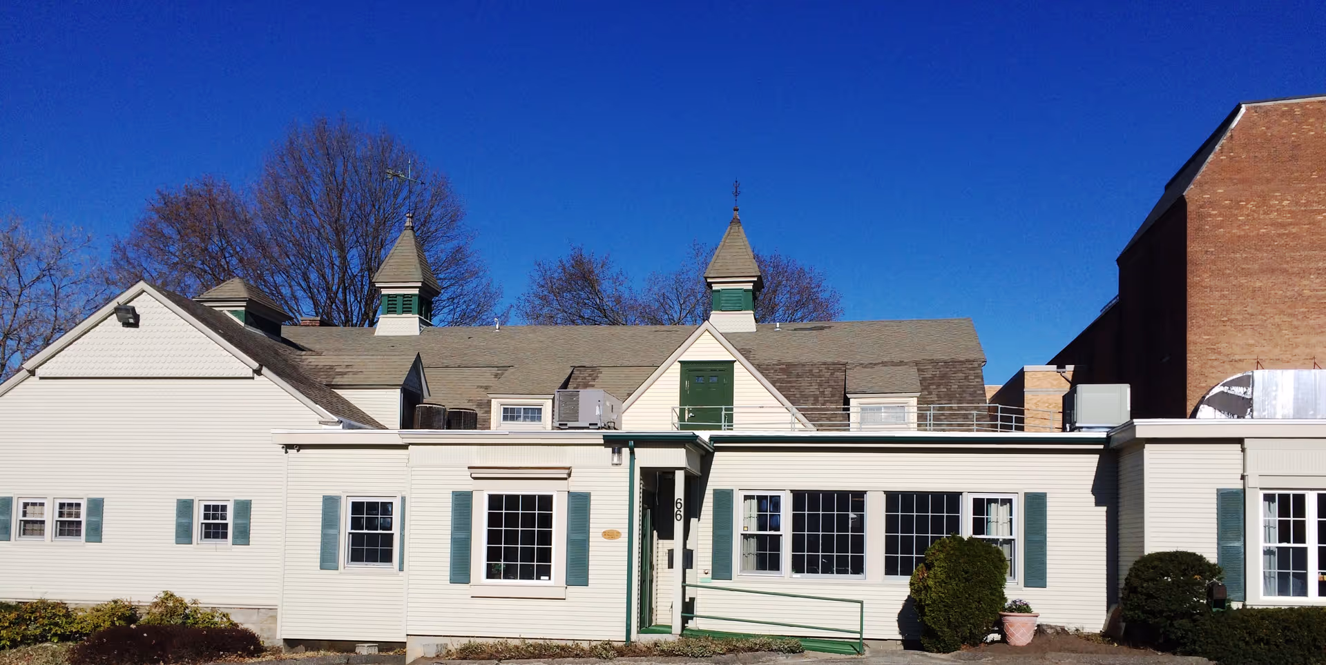 Exterior view of a single-story senior living building with white siding and green shutters.