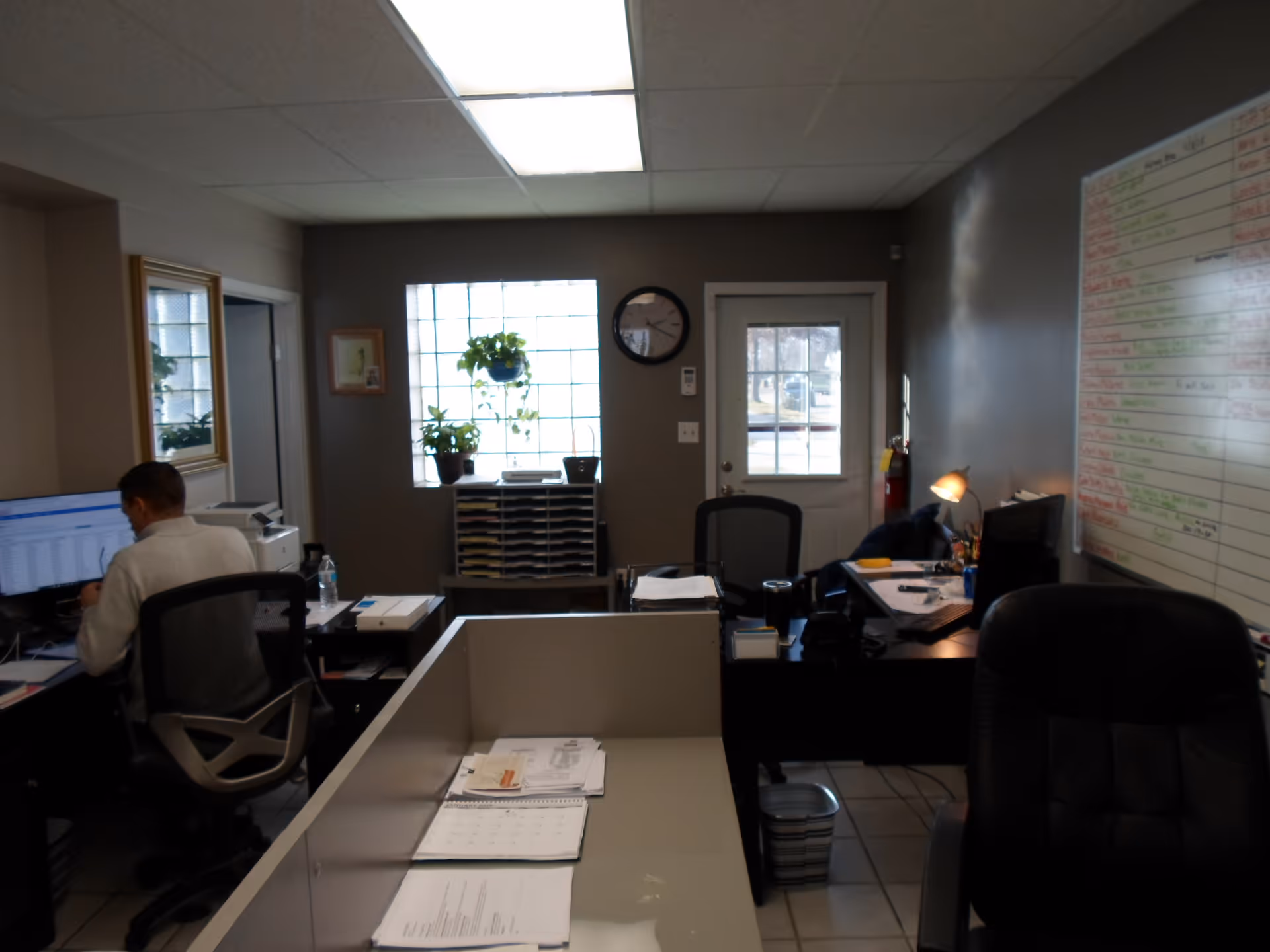 Office workspace inside a senior care facility with desks and staff at computers.