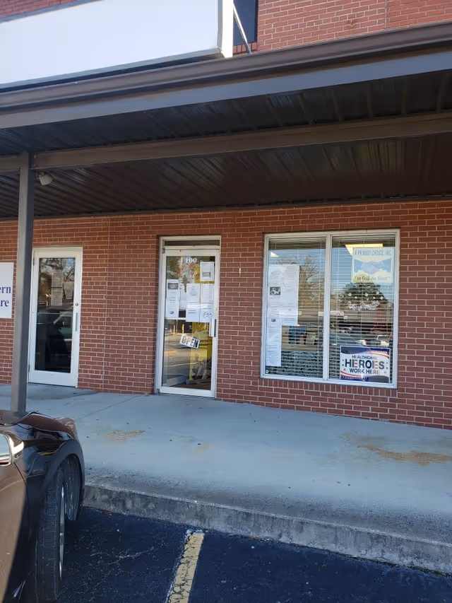 Brick building exterior with a covered entrance and glass doors.