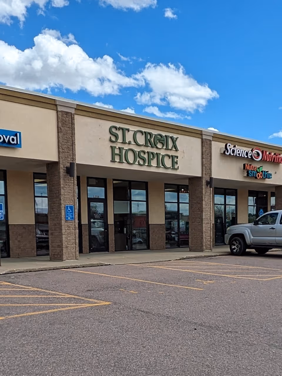 Exterior of a strip mall showing St. Croix Hospice sign and parking spaces.
