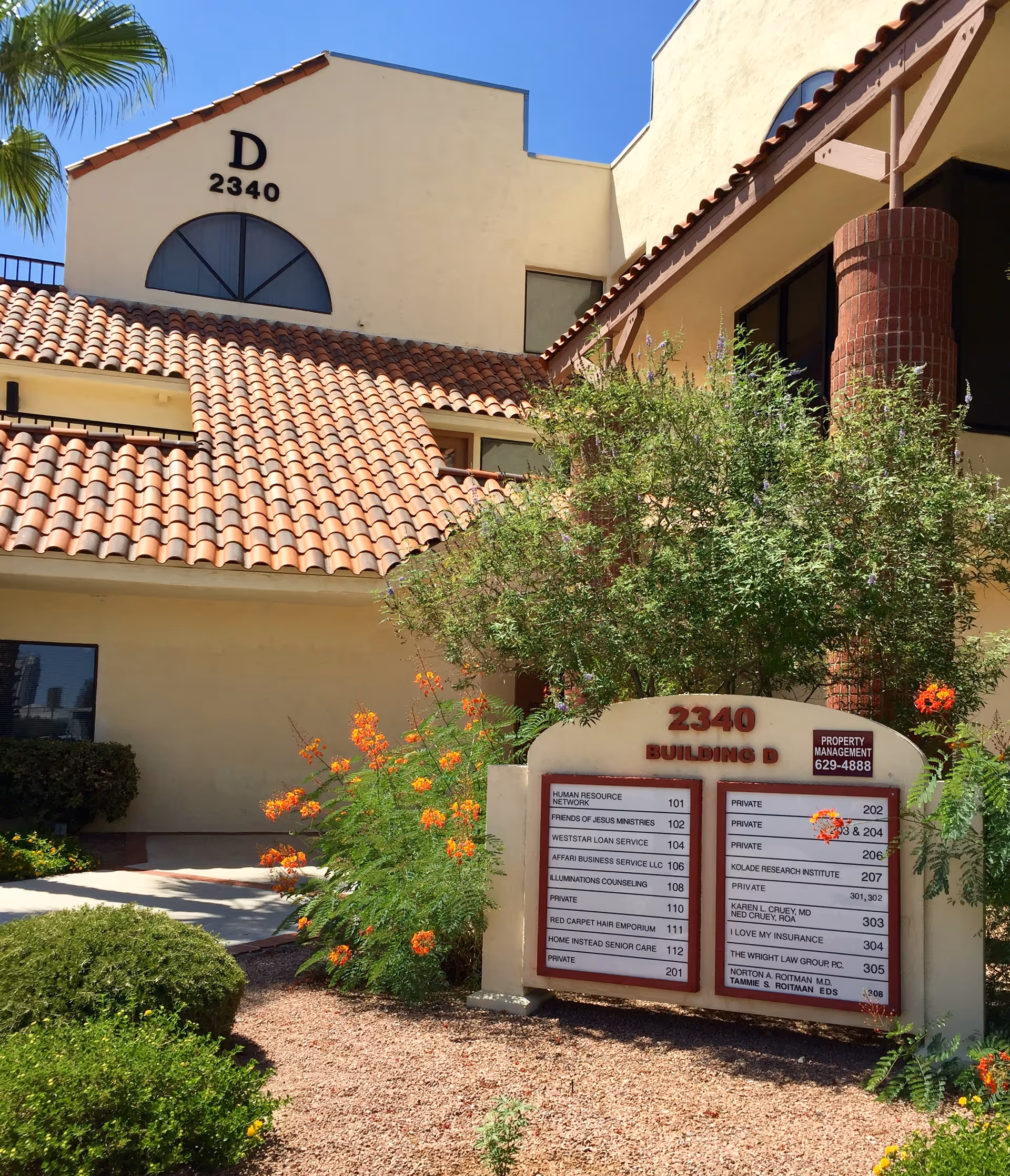 Exterior view of a senior living building with a tiled roof and a sign.